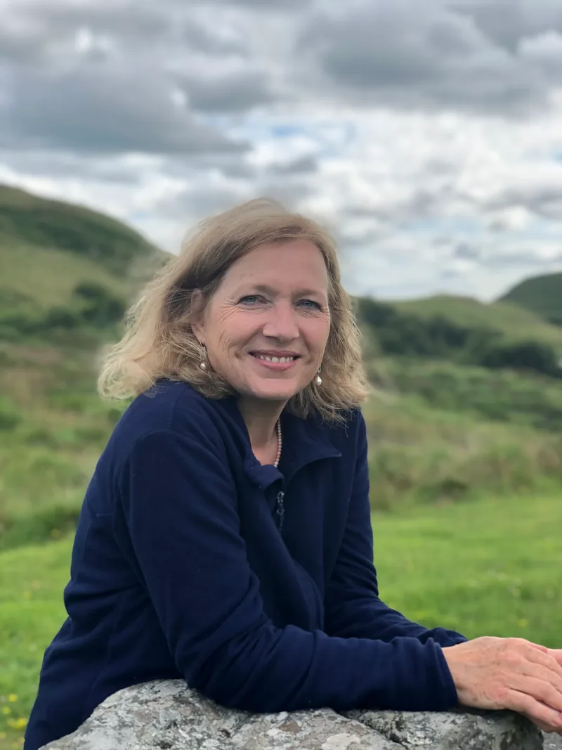 Eliane Zimmermann an einen Felsen gelehnt in der grünen Hügellandschaft Südwest-Irlands