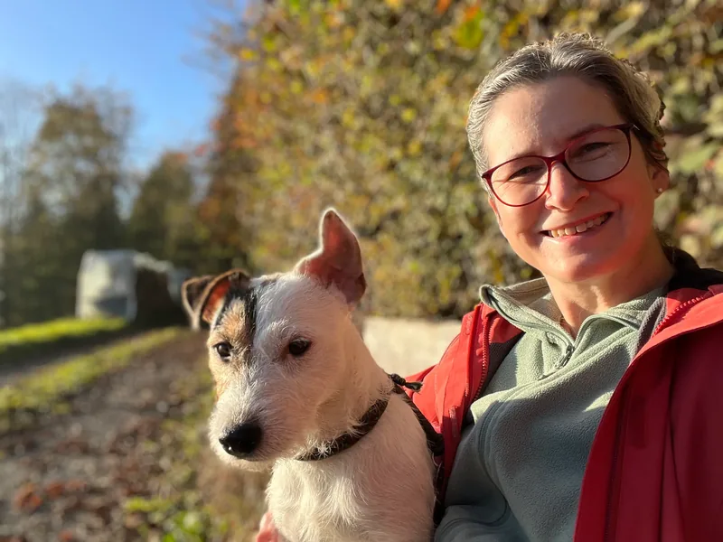 Sibylle Broggi-Läubli im Herbst draussen, mit ihrem Jack-Russell-Terrier auf dem Arm